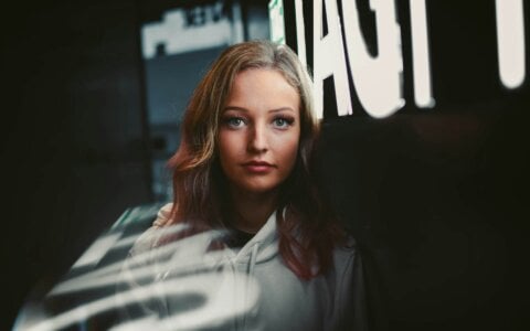 Dansk pige med hættetrøje, der kigger ind i kameraet – repræsenterer danske tøjmærker, der samarbejder med tøjproducenter i Indien såsom hættetrøjeproducent Indien, T-shirtproducenter Indien, økologisk tøjproducent Indien, herretøjproducenter Indien og andre indiske tøjproducenter.