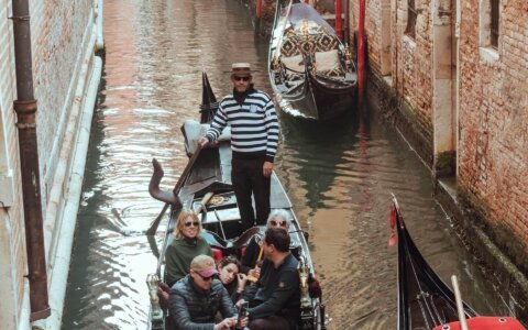 Uomo che guida una barca a Venezia, simbolo della connessione tra brand italiani e produttori di abbigliamento in India, inclusi produttori t-shirt India, produttori felpe con cappuccio India, produttori abbigliamento uomo India e produttori abbigliamento bambini India.